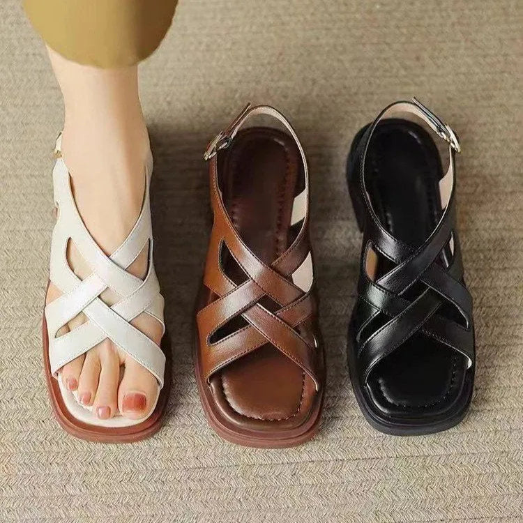 Women's black patent leather square toe beach sandals with cross strap design on a white background