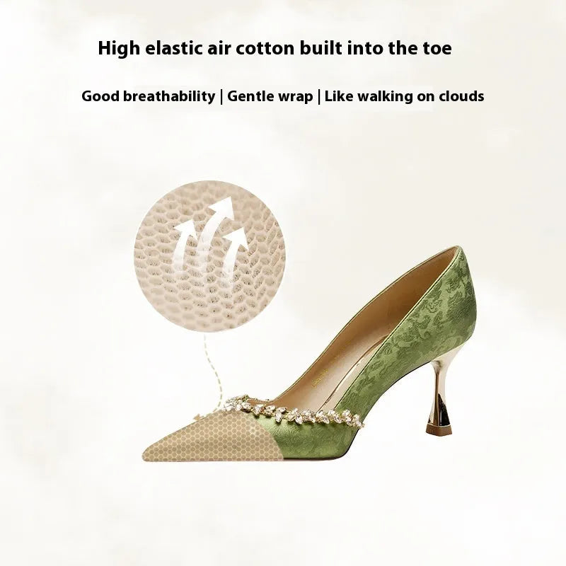 Women's champagne satin high heel wedding shoes with rhinestone decoration on a white background.
