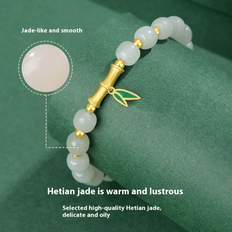 Women's bracelet with Hetian jade bead and sterling silver bamboo leaf charm on a wrist.