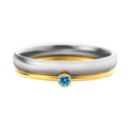 Close-up of a titanium steel ring with an engraved geometric design and a December colour birthstone.