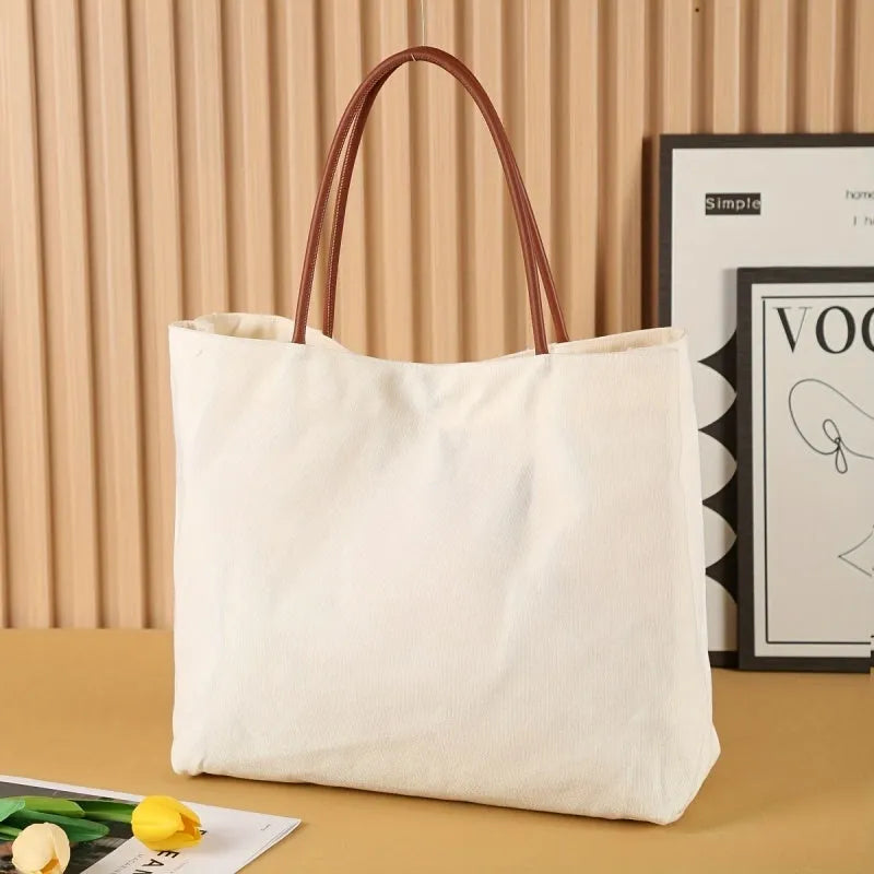 Beige white canvas tote bag with top handles and an internal zip pocket, shown with a book and keys.
