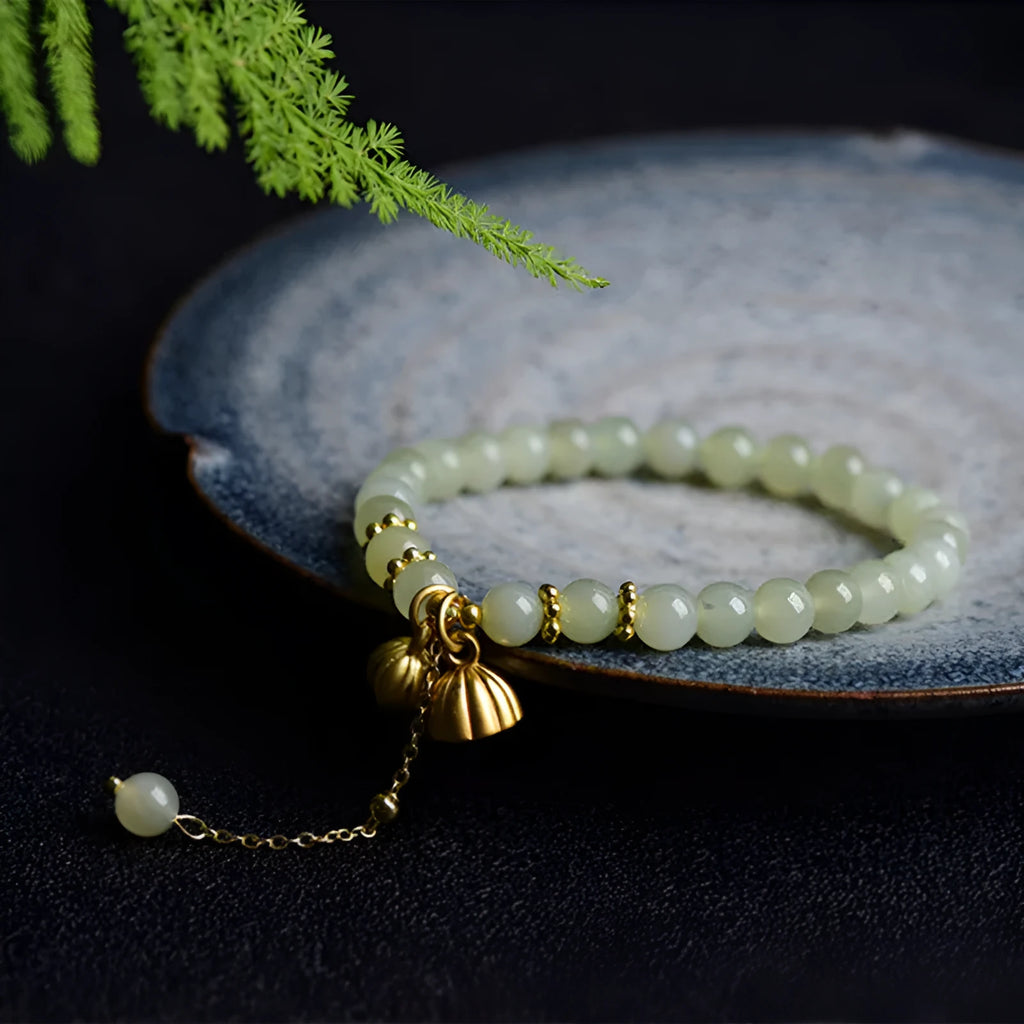 Natural Hetian jade bracelet with a carved Fu character charm on a wrist.
