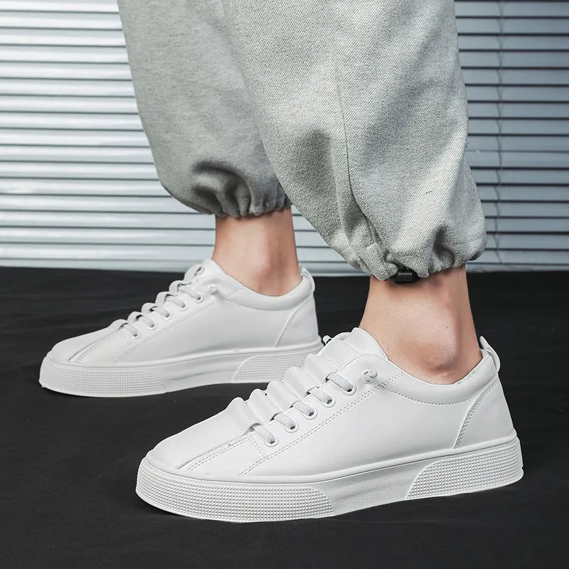 Men's black and white low top synthetic leather sports shoes with PVC sole on a plain background.