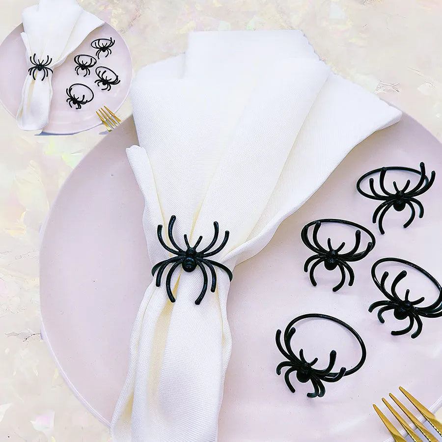 Set of six black alloy spider-shaped napkin rings for Halloween table decoration.